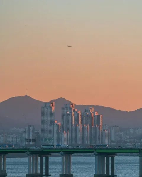 해 질 녘 하늘 아래 다리와 먼 도시 풍경